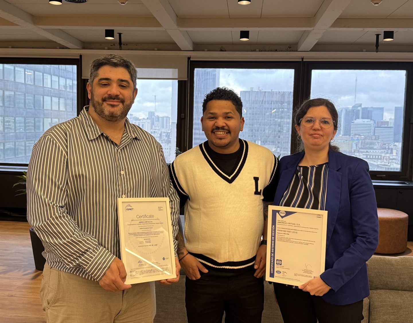 Tres integrantes del equipo de América Virtual sosteniendo los certificados enmarcados de IQNet e IRAM que acreditan la norma ISO 9001:2015.